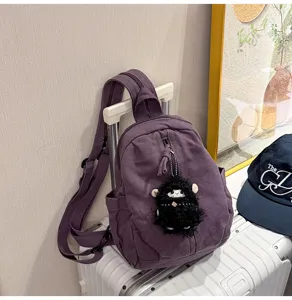Detailansicht des lila gewaschenen Canvas-Minirucksacks mit süßem schwarzen Plüschschaf-Anhänger.