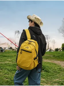 Homme portant un sac à dos extérieur jaune vif dans un champ herbeux pittoresque