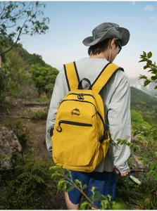 Sac à dos de randonnée jaune léger porté par un marcheur sur un sentier de montagne