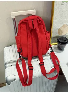 Roter multifunktionaler Segeltuch Rucksack Detailansicht mit Schultergurten auf einem Koffer.