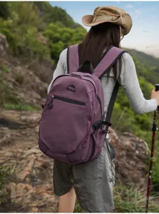 Randonneuse portant un sac à dos d'extérieur violet sur un sentier de montagne