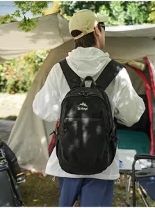 Vue de dos d'une personne portant un sac à dos noir sur un site de camping.