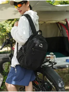 Sac à dos de randonnée noir présenté sur mannequin en décor de camping et vélo