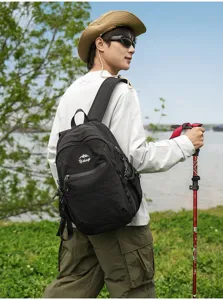 Randonneur asiatique portant un sac à dos d'extérieur noir avec un bâton de marche en plein air