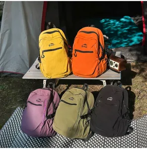 Cinq sacs à dos de randonnée décontractés de différentes couleurs dans un camping.