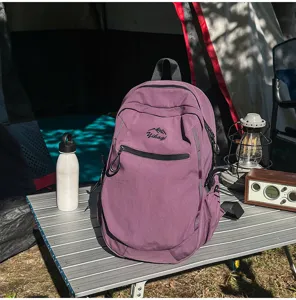 Sac à dos de randonnée violet sur table de camping avec radio vintage et lanterne