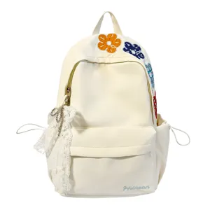 Detailansicht des Canvas-Rucksacks mit gesticktem Blumenmuster und Spitzenanhänger Dekoration.