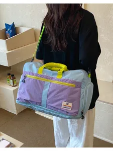 Large capacity color-block outdoor travel bag shown carried over the shoulder for detail