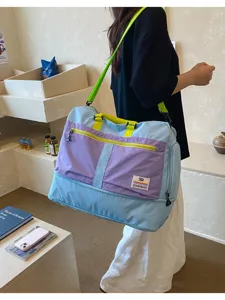 Detailed view of a large capacity outdoor color-block travel bag being worn by a model