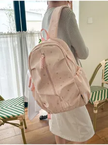 Zaino scolastico rosa con stampa a stelle indossato da una modella in interni.