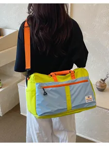 Large colorblock duffel bag worn by model, showing bright yellow and blue canvas panels