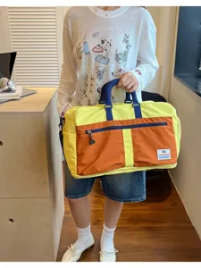 Detailed view of a large capacity color-blocking outdoor travel bag held by a model.