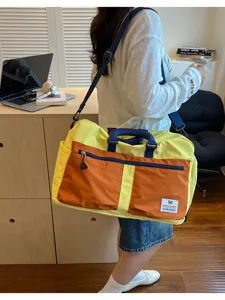 Large capacity color-blocked duffel bag worn by model in a minimalist study setting