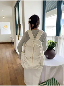 Vista posteriore di una modella con uno zaino color crema con stampe a stelle