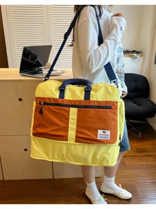 Large color-blocked outdoor travel duffel bag with shoulder strap carried by a model indoors