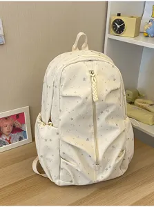 Vista frontale dello zaino scolastico crema con motivo a stelle su scrivania in legno