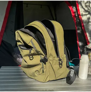 Vue détaillée de profil d'un sac à dos de randonnée vert olive sur une table de camping