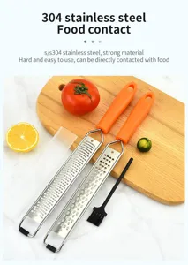 Stainless steel cheese grater and lemon zester tool with orange handle and cleaning brush.