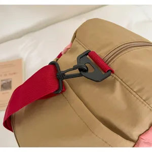 Detailed macro view of durable red shoulder strap hook on khaki ripstop travel duffel bag