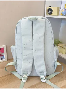 Vista posteriore di zaino scuola azzurro con stelle e spallacci su tavolo legno