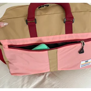 Close-up of front zipper pocket on large capacity color-block travel bag showing fabric detail