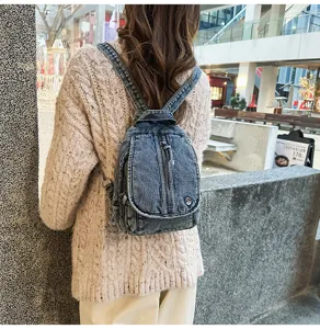 Rückansicht eines verwaschenen Denim-Rucksacks getragen mit einem beigen Zopfstrickpullover