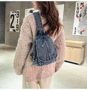 Detailansicht eines vintage gewaschenen Jeans-Rucksacks über einem groben Strickpullover