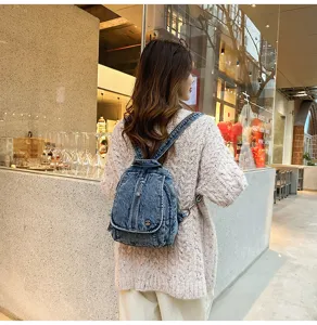 Nahaufnahme der verwaschenen Denim-Textur dieses stylischen kleinen Rucksacks am Model
