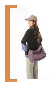 Nahaufnahme einer lila Vintage-Canvas-Umhängetasche mit Klappe an einem Modell