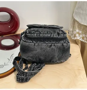 Detailansicht der Textur und des verstellbaren Riemens des grauen Denim-Rucksacks.