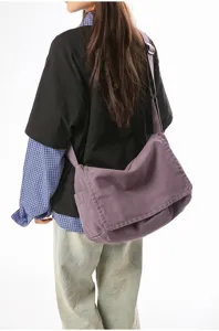 Rückansicht einer Frau mit einer violetten Vintage-Umhängetasche aus Canvas vor weißem Hintergrund