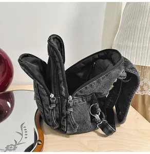 Detailansicht der gewaschenen Jeans-Brusttasche mit mehreren Reißverschlüssen.