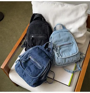 Vintage washed denim backpacks in black, light blue, and dark blue on a white chair.