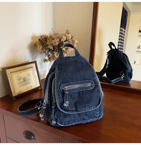Stylish vintage washed blue denim backpack for women displayed on a wooden cabinet