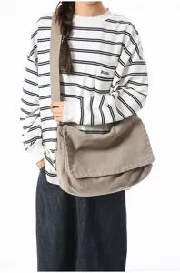 Vintage khaki Segeltuch Umhängetasche mit Klappe, getragen von einem Model in Freizeitkleidung