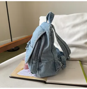 Detailed side view of a vintage washed light blue denim backpack resting on an open book