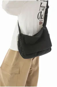 Nahaufnahme einer schwarzen Vintage-Canvas-Umhängetasche mit Klappe am Modell