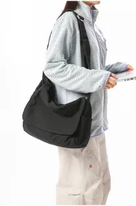 Asiatisches Model mit einer vintage schwarzen Canvas-Umhängetasche mit Klappenverschluss