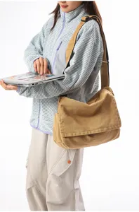 Professionelles Model trägt eine khakifarbene Canvas-Umhängetasche und hält einen Laptop.
