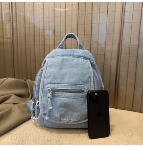 Detailed view of the mini blue denim backpack next to a smartphone for size reference