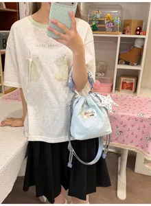 Primo piano di una graziosa borsa a secchiello azzurra con ciondolo a stella trendy
