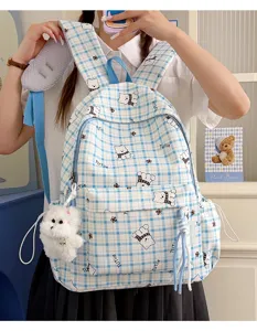 Detailed view of blue plaid schoolbag with bear patterns and plush puppy charm