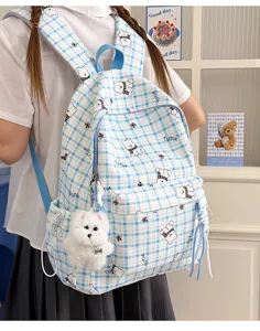 Detailed view of blue checkered backpack with cute cartoon bear print and plush charm