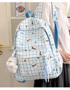 Detail view of a blue plaid backpack with cute bear patterns and plush keychain.