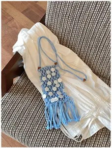 Close-up of blue macramé phone bag with shell accents and fringe detail