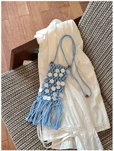 Detailed view of handmade blue macrame phone bag with shell sequins and long tassels.