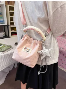 Dettaglio di una borsa a secchiello rosa in stile giapponese con ciondolo a forma di stella.