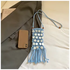 Detailed macro view of light blue hand-woven crochet phone bag with tassels and shell discs