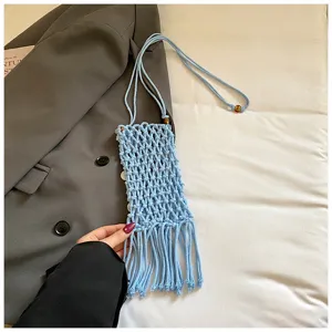 Macro view showing the detailed texture of light blue hand-woven macrame phone bag with fringe