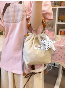 Dettaglio di una borsa a secchiello beige stile giapponese con ciondolo a stella e manico